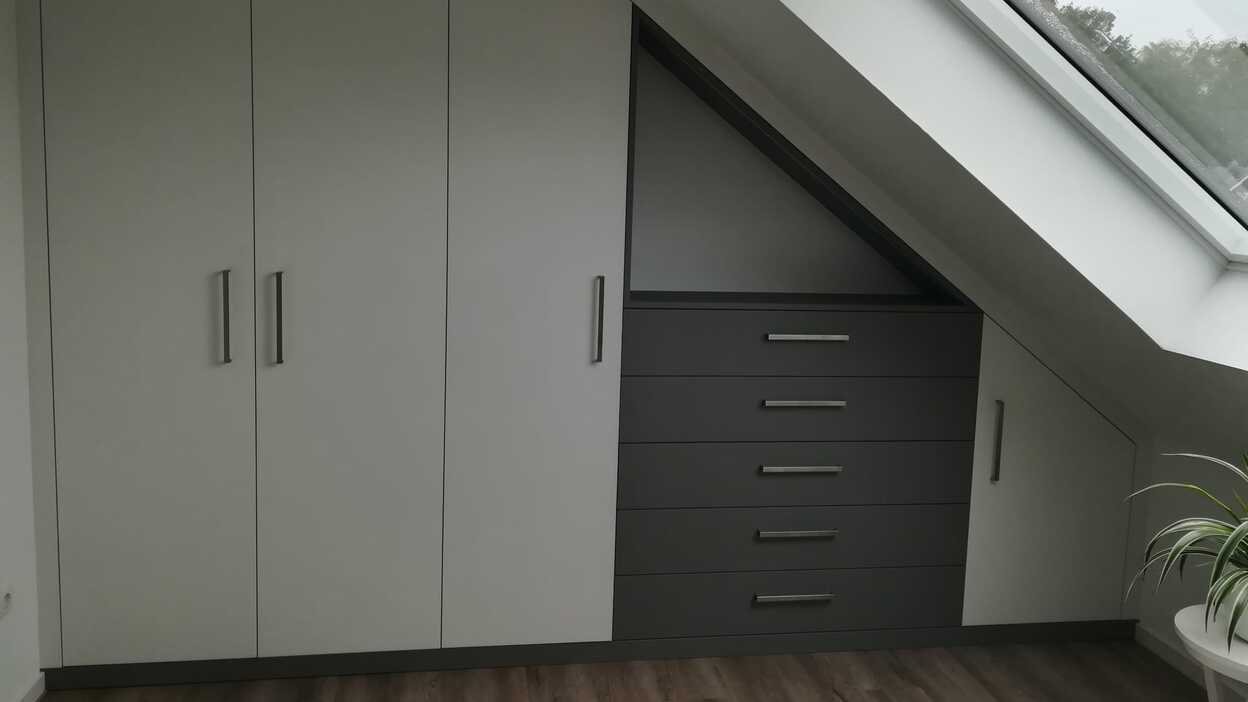 Einbauschrank nach Maß Individueller Einbauschrank nach Maß mit grauen Türen und Schubladen unter Dachschräge.