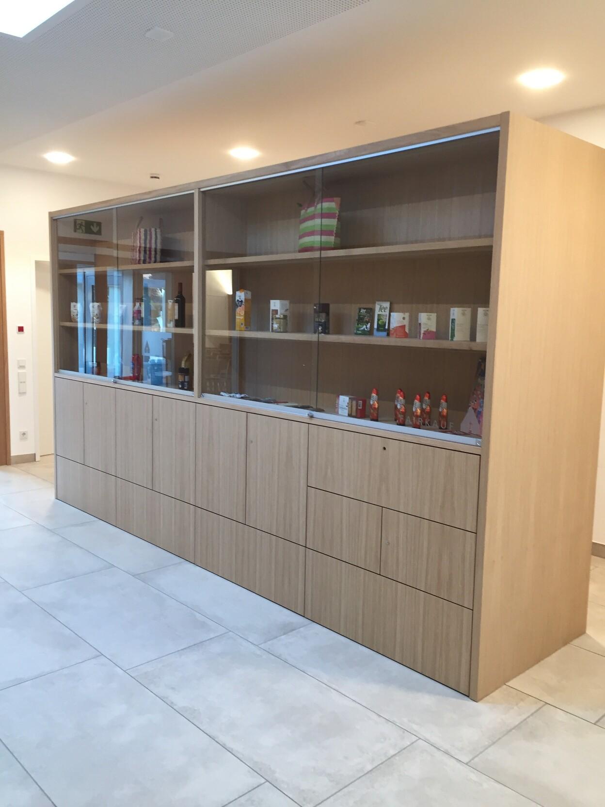Objekteinrichtung Maßanfertigung Moderne Objekteinrichtung mit maßgefertigtem Holzschrank, Glasvitrine und integriertem Stauraum.