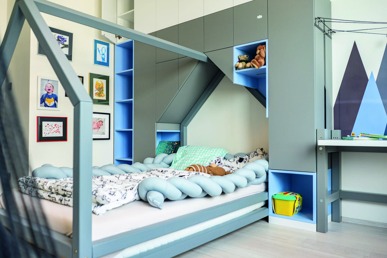 Modernes Kinderzimmer mit einem Bett im Häuschen-Design, samt dekorativen Bildern und Spielzeugregalen.