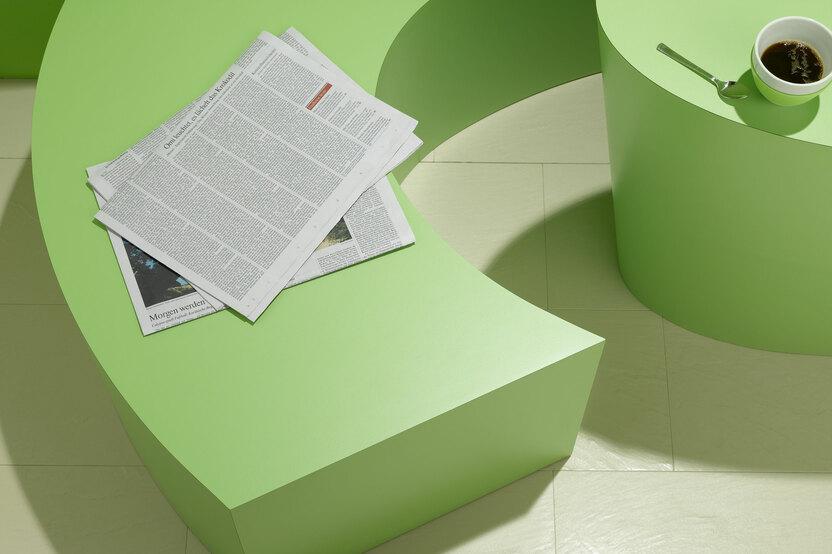 Detailaufnahme einer grünen Sitzbank Detailaufnahme einer grünen Sitzbank mit Papierdokumenten und Tischausschnitt mit Kaffeetasse