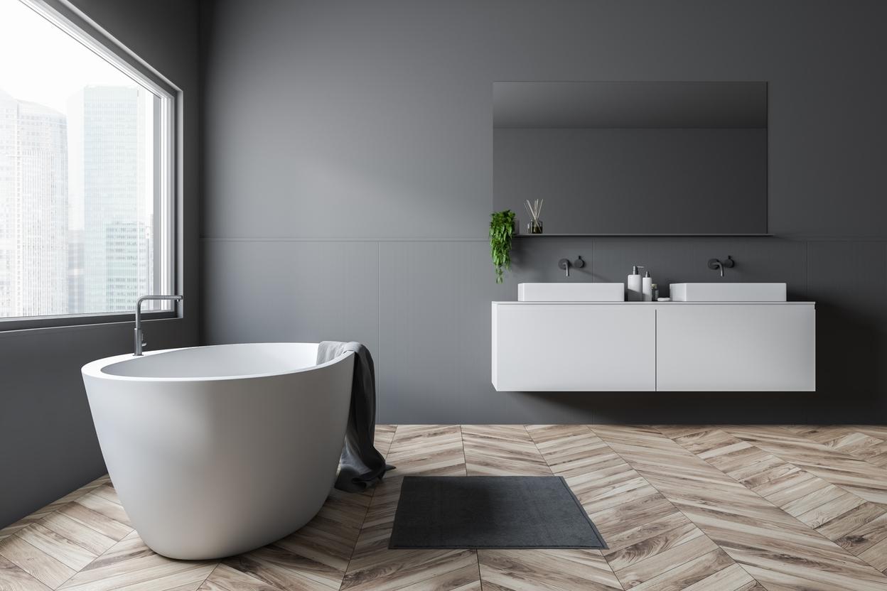 Cleane Badezimmerimpression in weiß mit Fischgrätenparkett Cleane Badezimmerimpression mit weißer Badewanne und Doppel-Waschtisch mit hellem Fischgrätenparkett.